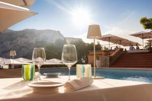 a table with wine glasses on a table next to a pool at Hotel Punta Tragara in Capri