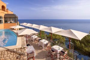 a resort with a pool and tables and umbrellas at Hotel Punta Tragara in Capri
