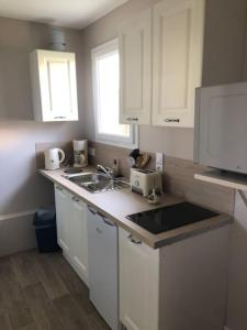 a kitchen with white cabinets and a sink at maison indépendante avec jardin in Senlis
