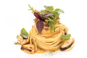 a pasta dish with oysters and greens on top at Hotel Punta Tragara in Capri