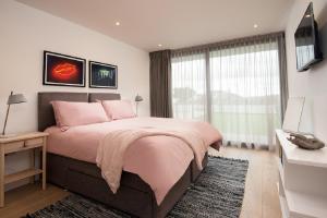 a bedroom with a pink bed and a large window at 1 The Bay - Stunning contemporary flat on the Scottish coast in Coldingham