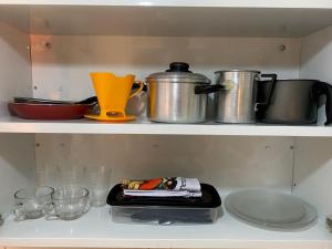 a kitchen shelf with pots and pans and glasses at Pousada Recanto dos Parente - Icaraizinho de Amontada in Amontada