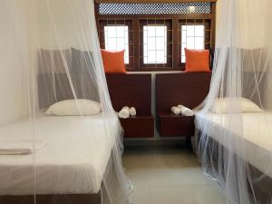2 letti in una camera con zanzariere di Island Star POOL & SPA a Galle