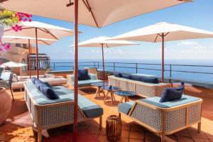 a deck with chairs and umbrellas and the ocean at Hotel Punta Tragara in Capri