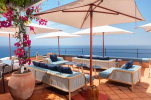a patio with tables and chairs and umbrellas at Hotel Punta Tragara in Capri