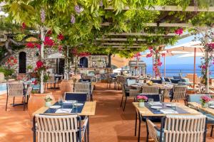 a restaurant with tables and chairs with the ocean in the background at Hotel Punta Tragara in Capri