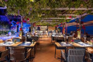 a restaurant with tables and chairs and plants at Hotel Punta Tragara in Capri