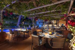 a restaurant with tables and chairs and plants at Hotel Punta Tragara in Capri