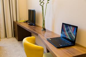 um computador portátil sentado numa secretária com uma cadeira amarela em Hotel Jelena em Banja Luka
