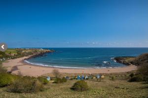 a beach with a group of huts and the ocean at 1 The Bay - Stunning contemporary flat on the Scottish coast in Coldingham