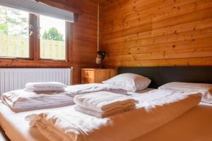 two beds in a wooden room with towels on them at Spacious wooden cottage with infra-red sauna at Veluwe in Putten