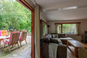 un soggiorno con divano e tavolo di Spacious wooden cottage with infra-red sauna at Veluwe a Putten