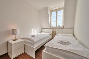 City Apartment Bern, perfect located and spacious في برن: سريرين في غرفة بيضاء مع نافذة