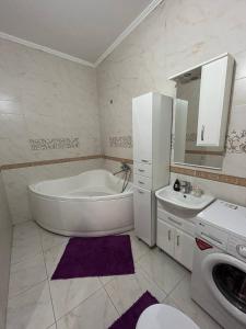 a bathroom with a tub and a sink and a washing machine at Просторная 3 комнатная квартира in Atyrau