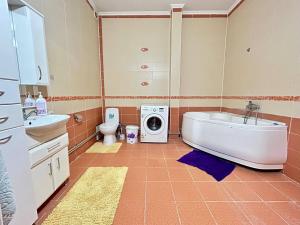 a bathroom with a tub sink and a washing machine at Просторная 3 комнатная квартира in Atyrau