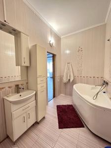 a white bathroom with a tub and a sink at Просторная 3 комнатная квартира in Atyrau