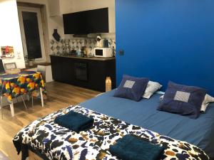a blue bedroom with a bed with pillows on it at La ti case - studio de charme au coeur du medoc in Saint-Laurent-de-Médoc