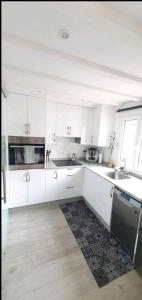 une cuisine blanche avec des placards blancs et une fenêtre dans l'établissement Casa Loft con terraza vigo, à Vigo