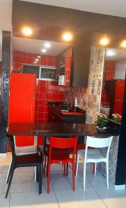 cocina con paredes rojas, mesa negra y sillas en Ilha do Caribe 02 quartos, en João Pessoa