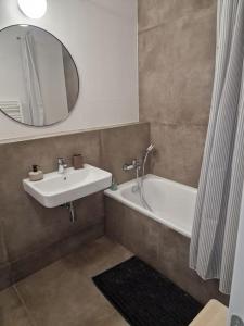 a bathroom with a sink and a tub and a mirror at Stylish Urban Residence with parking spot in Nivy