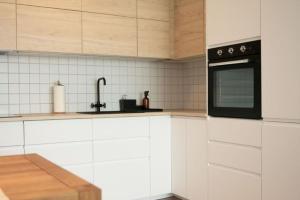 a kitchen with white cabinets and a black microwave at Stylish Urban Residence with parking spot in Nivy