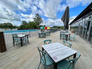 a deck with tables and chairs and a pool at Wildflower, Premium Plus Hot Tub Lodge in South Cerney