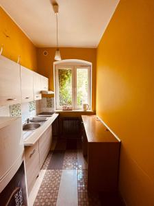 een gele keuken met een wastafel en een raam bij Stare Miasto in Zielona Góra