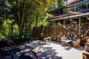 eine Terrasse mit Stühlen, Tischen und einer Steinmauer in der Unterkunft Euro Hotel Gradche in Kočani