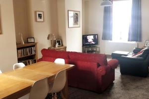 a living room with a red couch and a table at Stunning comfortable home from home in Millom