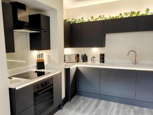 eine Küche mit schwarzen und weißen Schränken und einem Waschbecken in der Unterkunft Carvetii - ANNE House Room 1 - Dbl bed Ground floor en-suite in Carlisle