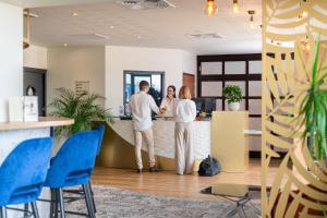 Le Mauritia Hotel et Spa في بورنيك: رجل وامرأة يقفان في مكتب