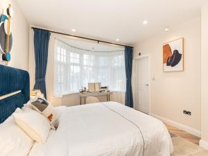 1 dormitorio con 1 cama blanca grande y escritorio en Pass the Keys Bright and Airy 3BR New Flat near Central London, en Londres