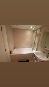 a bathroom with a bath tub and a sink at Private room in Camden in London