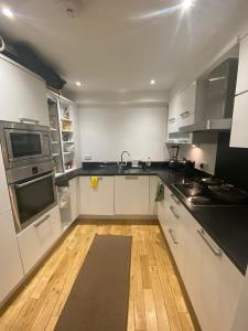 a kitchen with white cabinets and a wooden floor at Private room in Camden in London