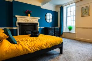 a blue bedroom with a bed with a yellow blanket at Albert's Place in Weymouth