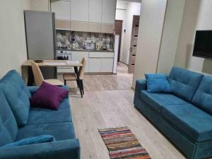 a living room with two blue couches and a kitchen at Recently built, new apartment Tbilisi in Tbilisi City