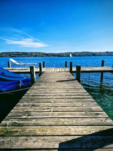 muelle de madera con un barco en el agua en Sommertraum mit eigenem Steg und Liegewiese, en Pöcking