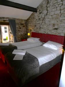 duas camas num quarto com uma parede de pedra em The George Inn em Skipton
