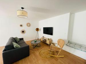 een woonkamer met een bank en een tv bij L'Escapade Nîmoise - climatisation in Nîmes