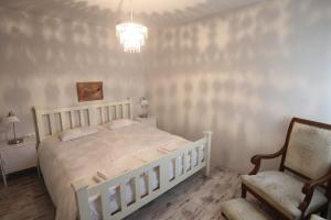 sypialnia z łóżkiem, krzesłem i żyrandolem w obiekcie Pastel Guesthouse w Balatonfüred