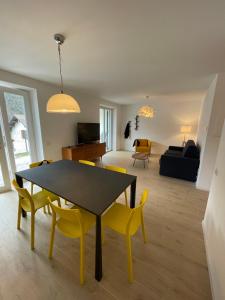 jadalnia i salon ze stołem i żółtymi krzesłami w obiekcie Appartamento Getaway Ledro w mieście Ledro