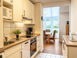 a kitchen with white cabinets and a sink and a table at Sünnslag Wohnung 131 in Boltenhagen