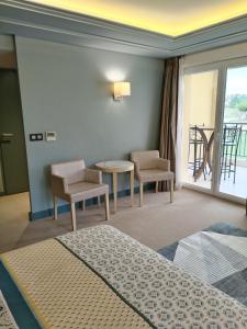 ジュヴィニャックにあるSuite Deluxe vue sur Golfのベッド、テーブル、椅子が備わるホテルルームです。