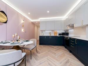 a kitchen with white cabinets and a table and chairs at Pass the Keys FLAT 2 Cozy Gem New 2 BR Near Central LondonWimbledon in London