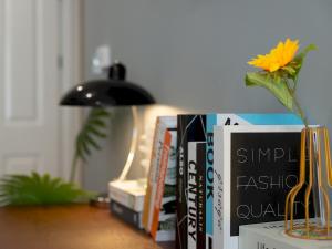 a pile of books sitting on a table with a vase at Pass the Keys FLAT 2 Cozy Gem New 2 BR Near Central LondonWimbledon in London