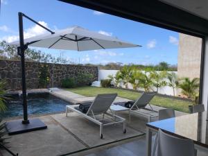a patio with two chairs and a table with an umbrella at Villa neuve et cosy, piscine privée et proche de Grand Baie in Pereybere