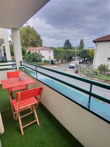 einen Balkon mit einem roten Tisch und Stühlen darauf in der Unterkunft Appartement Près Gare, Parking in Vigneux-sur-Seine