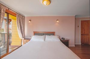 a bedroom with a large white bed and a balcony at Casa Vander Hotel Boutique in Valparaíso