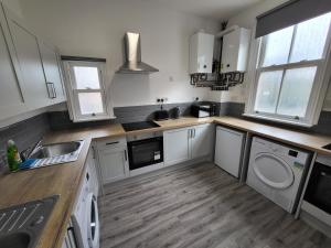 cocina con armarios blancos, fregadero y lavavajillas en Nottingham Forest Rd, Short Stays en Nottingham