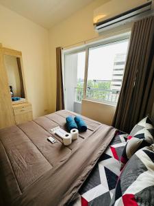 een slaapkamer met een bed met blauwe kussens en een raam bij Taguig 1 Bedroom with balcony Grace Residences Near Bgc in Manilla